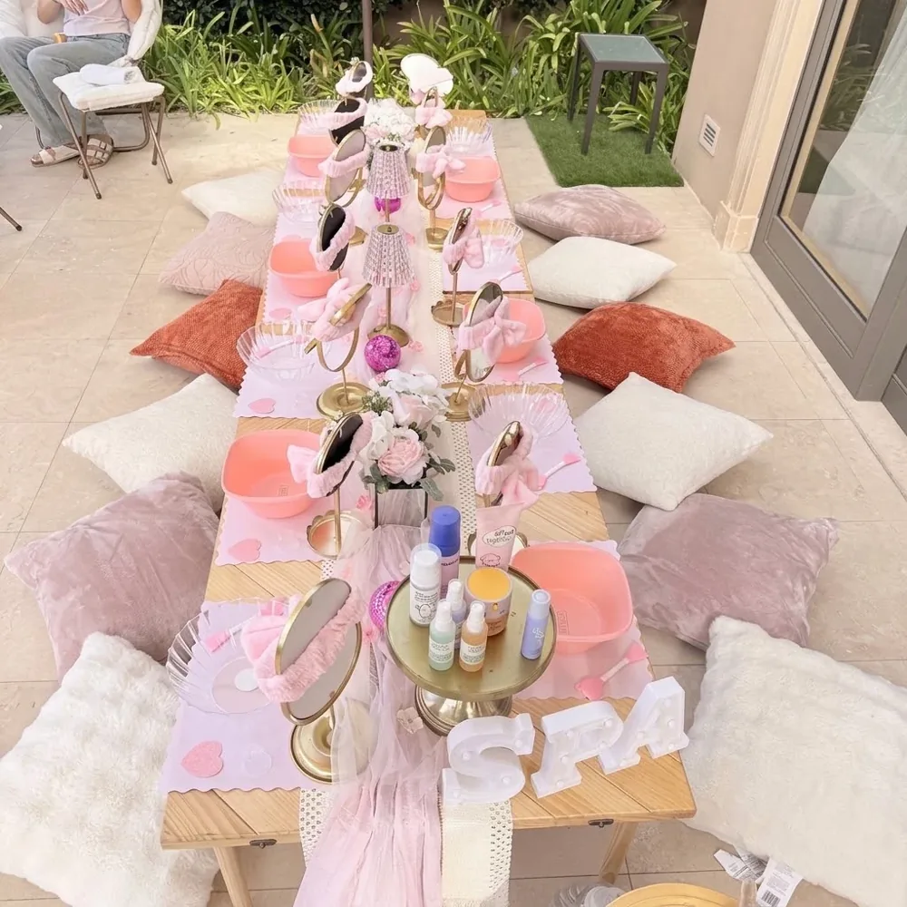 A pastel spa table lined with chairs, bowls, supplies, and floor cushions.