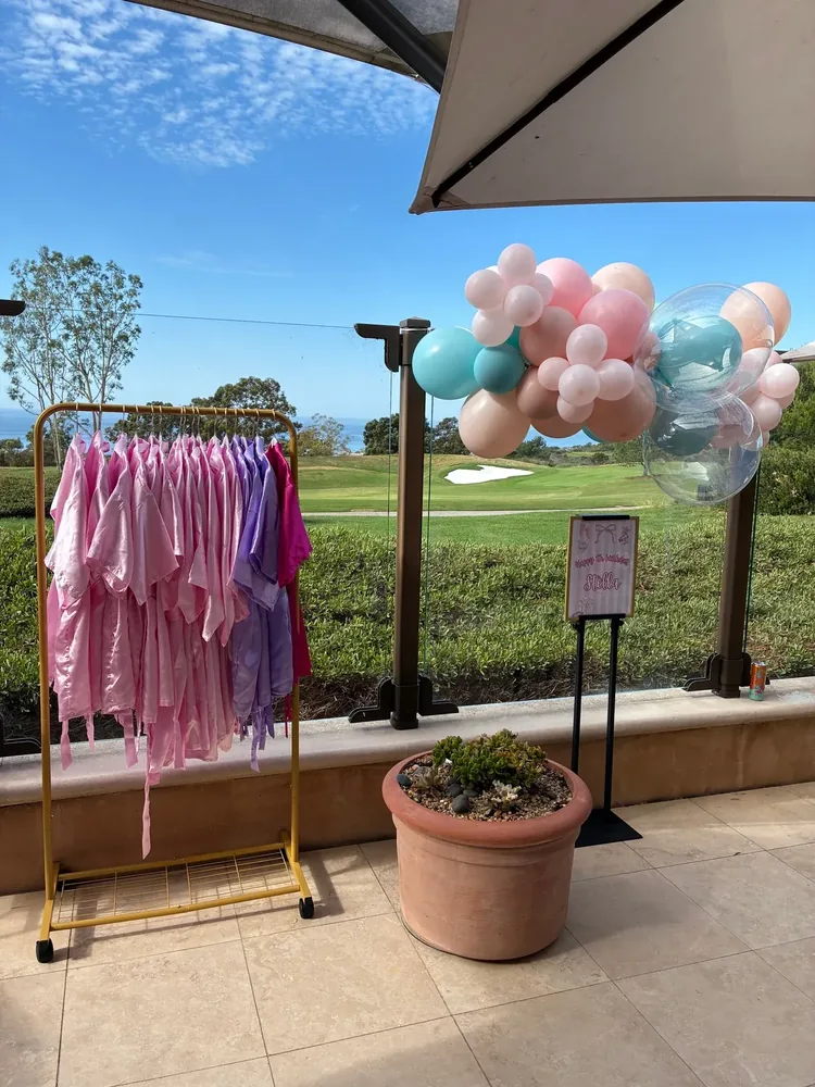 Pink and purple robes on a rack beside balloon decor.