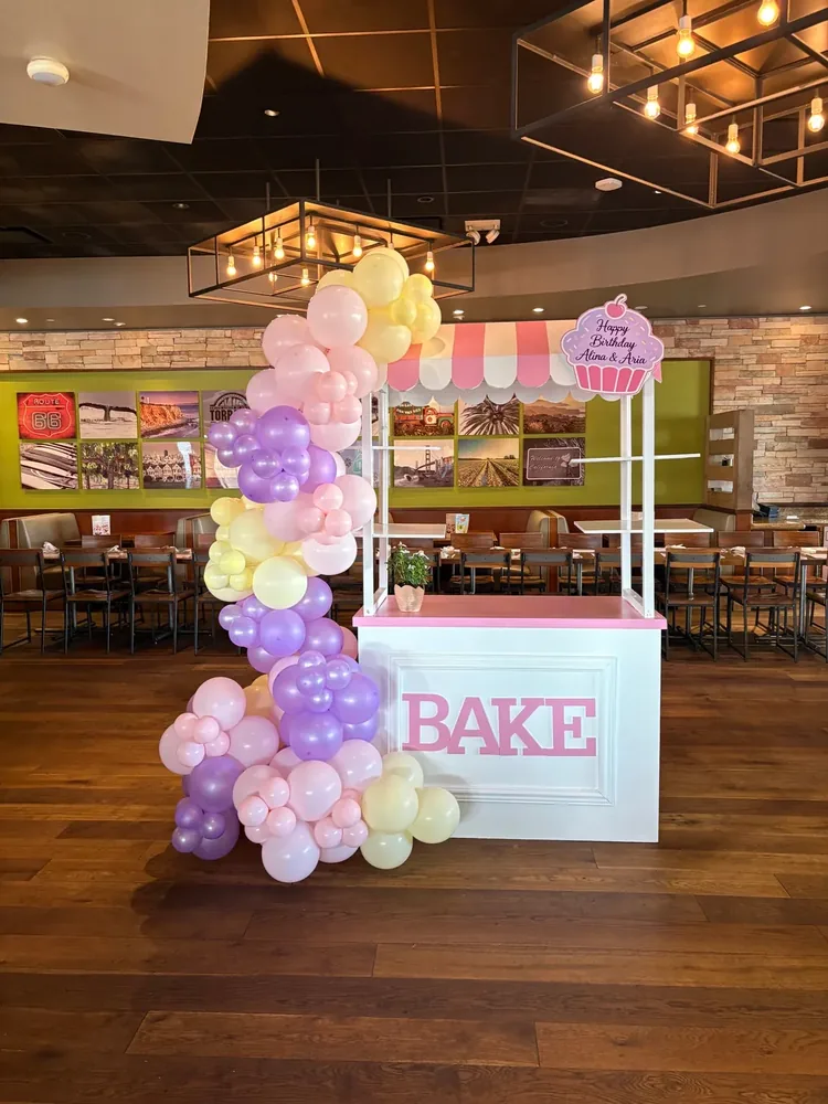 An indoor party cart with a balloon garland and birthday sign.