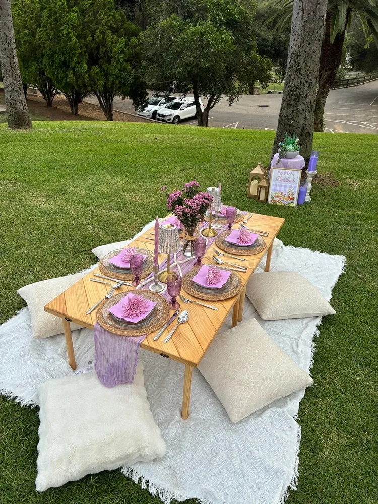 A low outdoor table dressed with place settings and floor cushions.