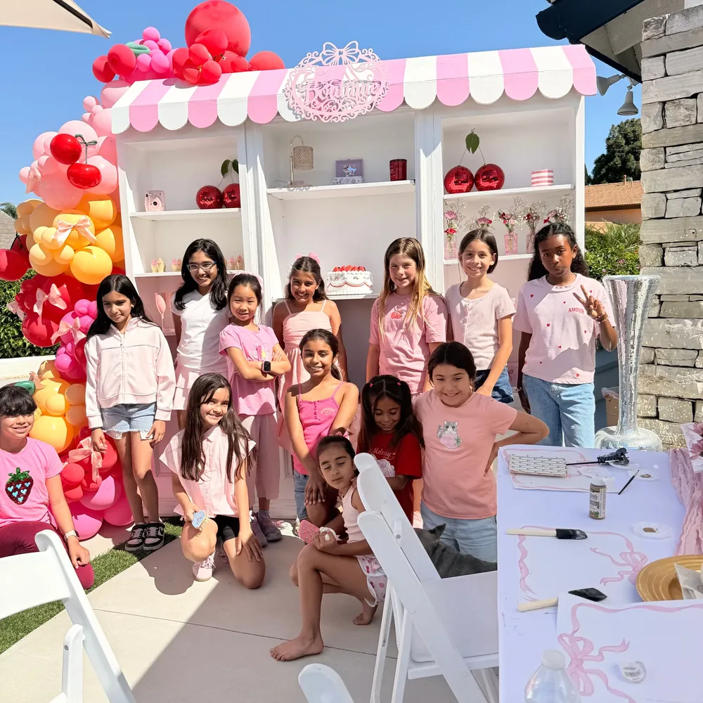 A group gathers in front of a pink-and-white GlamUpBash party display.