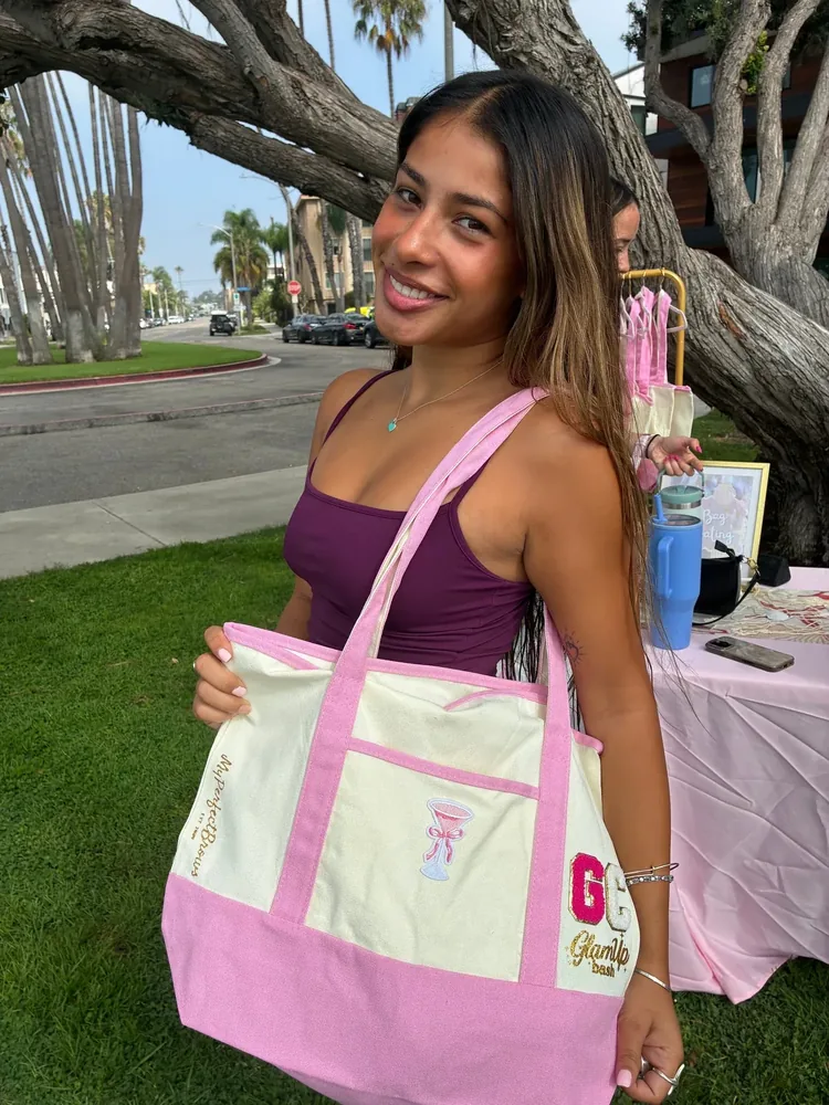 An adult guest holding a decorated tote beside an outdoor robe display.